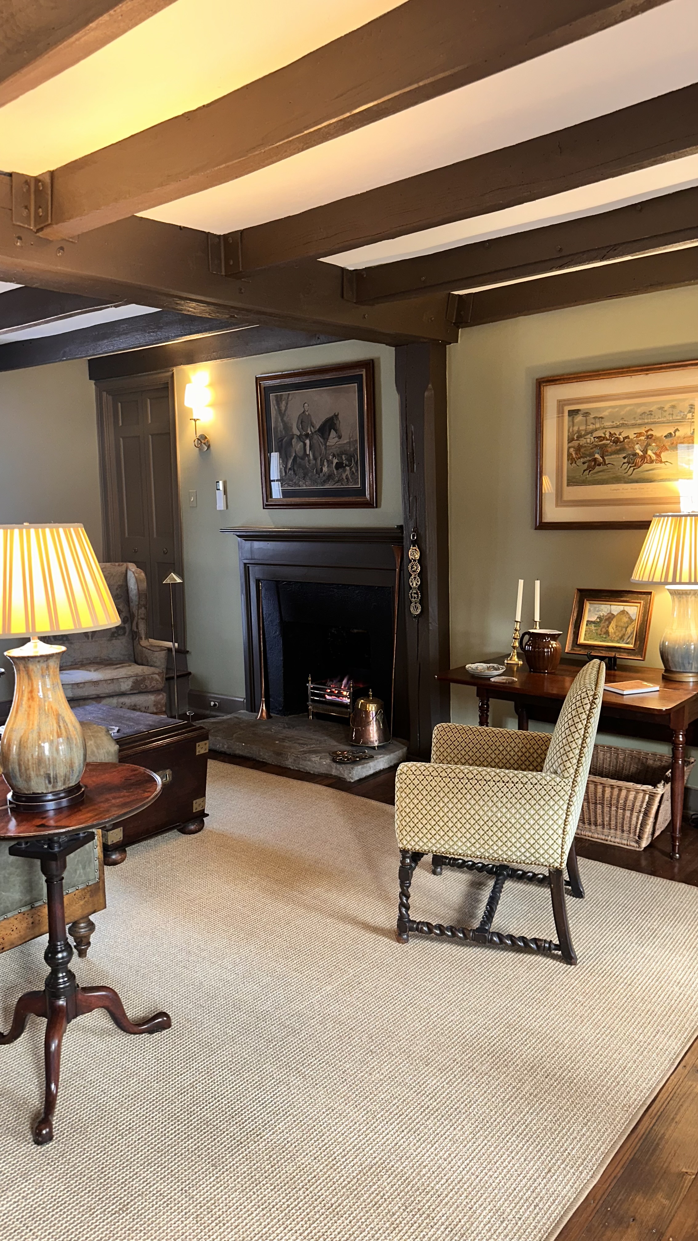 large room with Chesterfield sofa and chairs facing a fireplace for coal basket