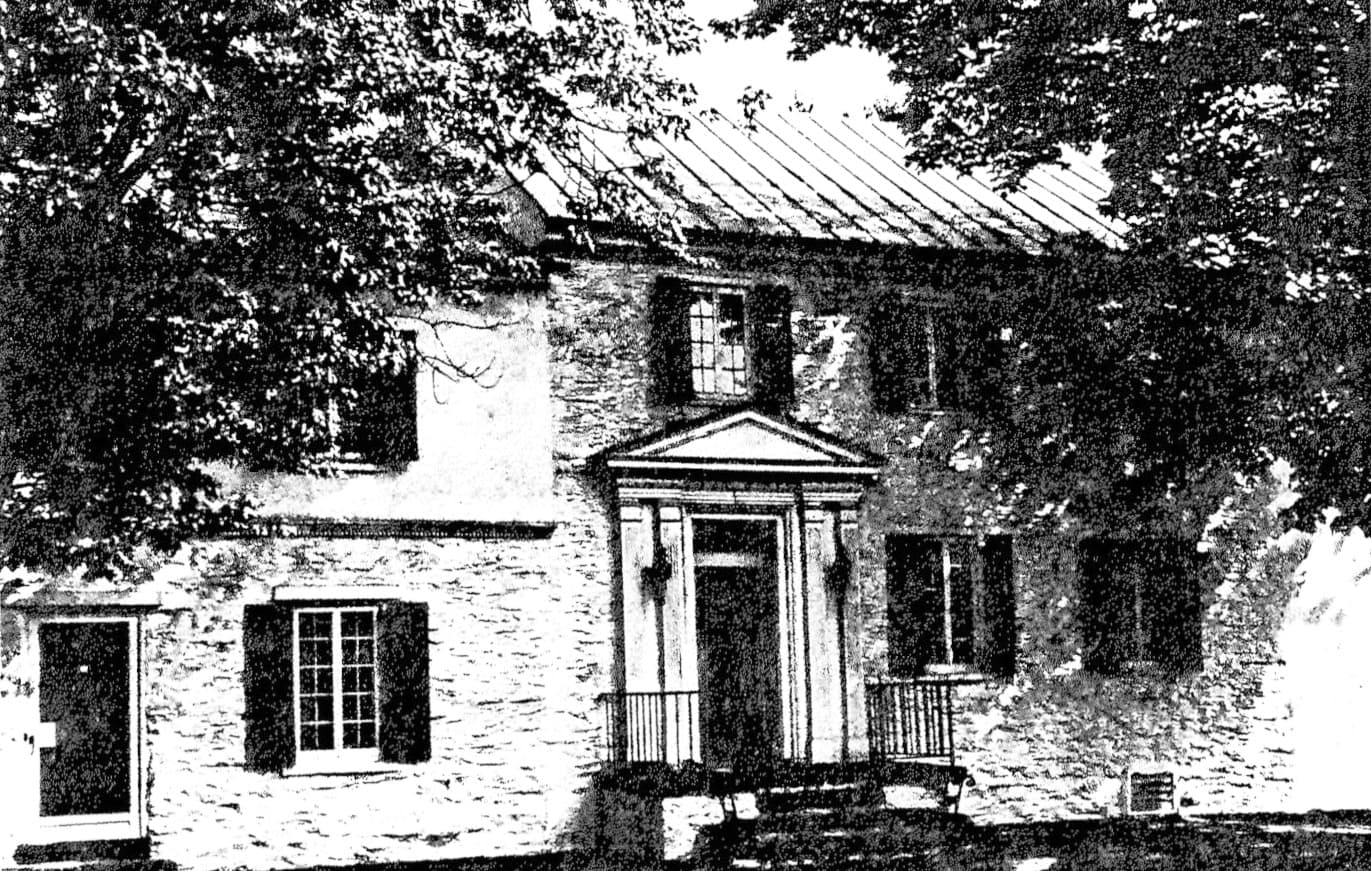 Black and white image of a historic house surrounded by trees.