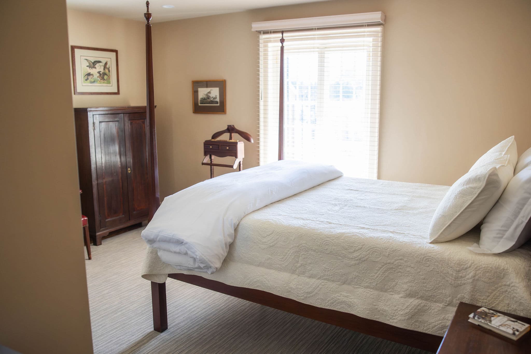 side view of queen pencil post bed and chest with chair beside it