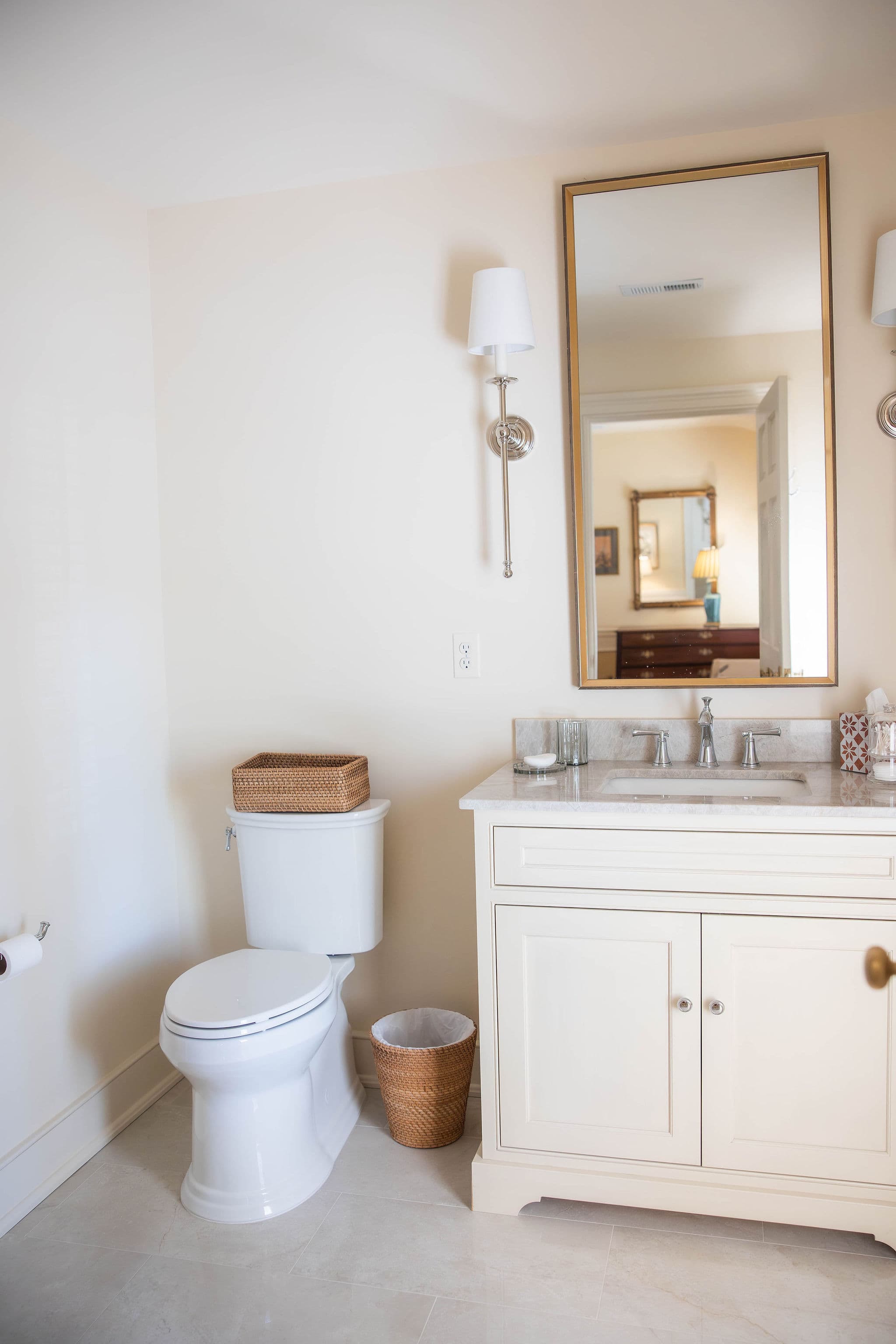A bright bathroom featuring a toilet, sink with countertop, and a large mirror.