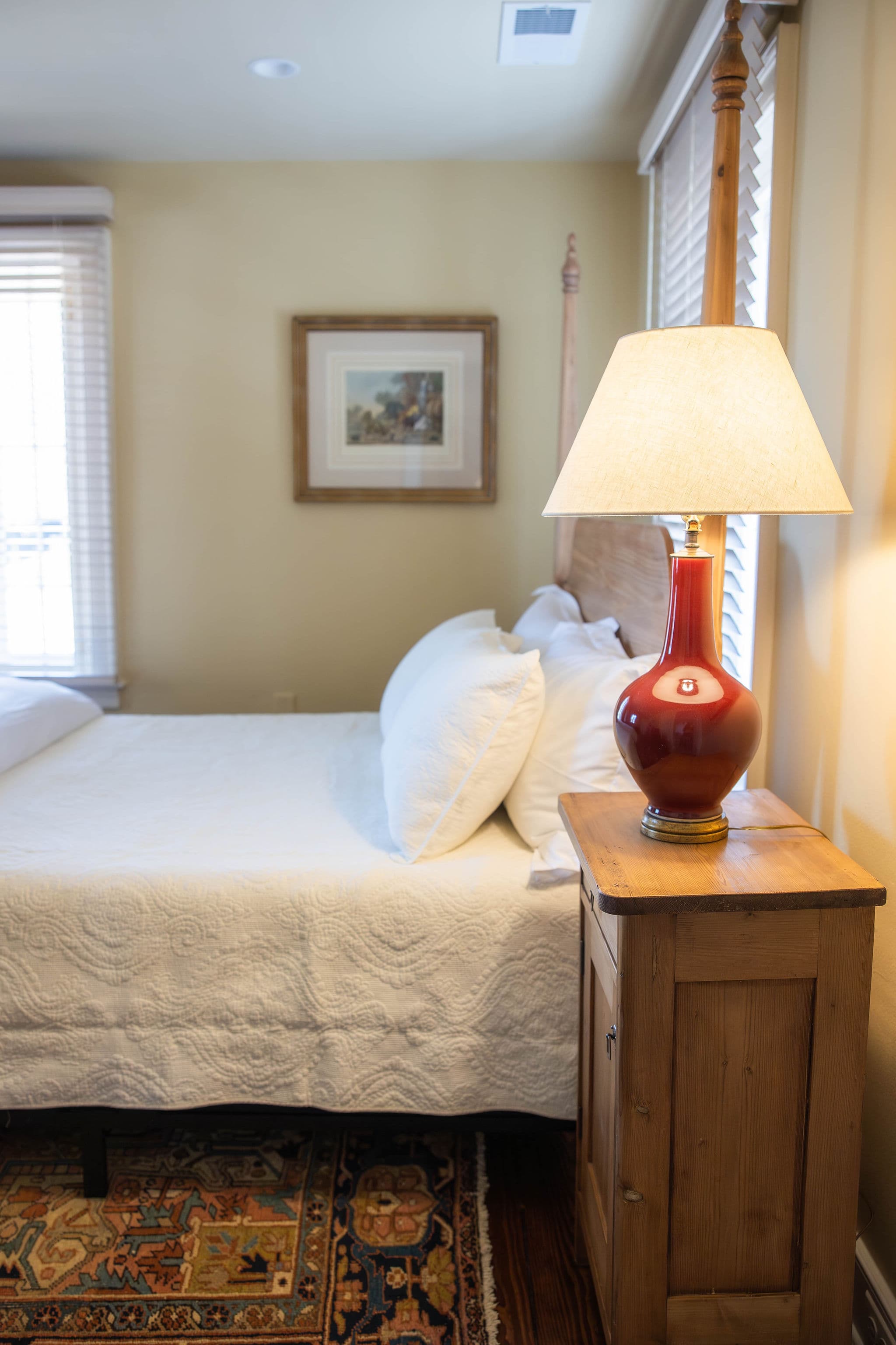 Side view of bed with bedside table and red lamp