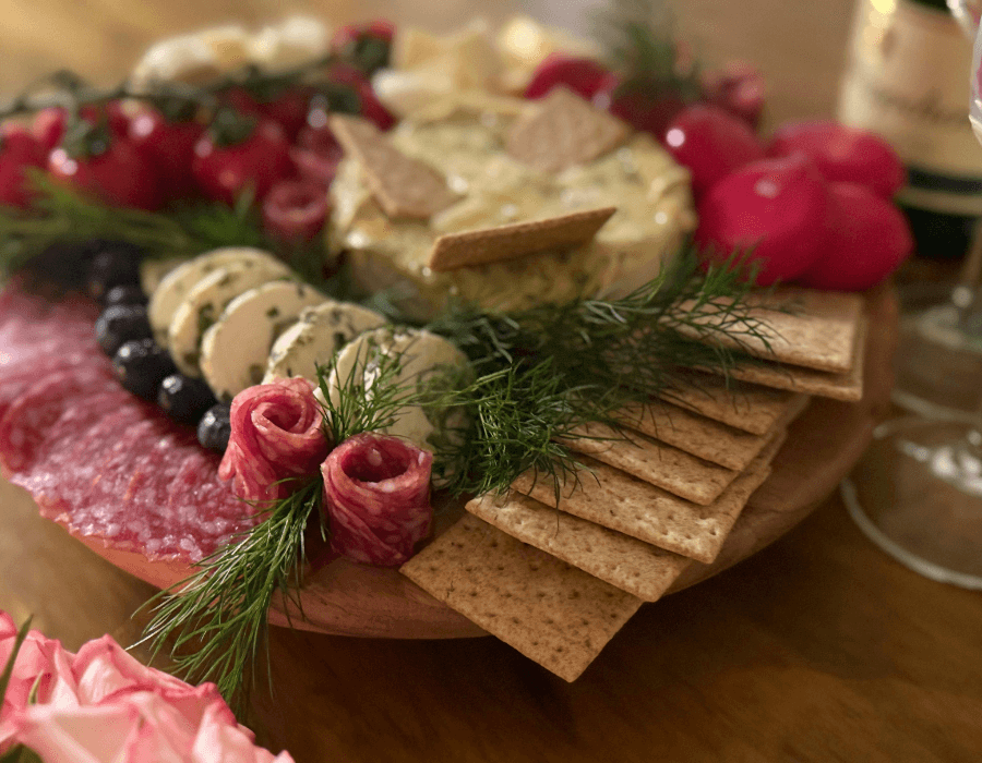 A beautifully arranged charcuterie board featuring assorted cheeses, meats, crackers, and fresh herbs.
